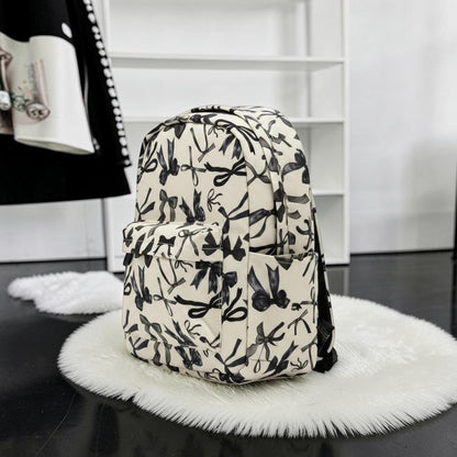 Little Britches Children's Boutique cream mini backpack with a black bow print, featuring a front pocket and side slots.